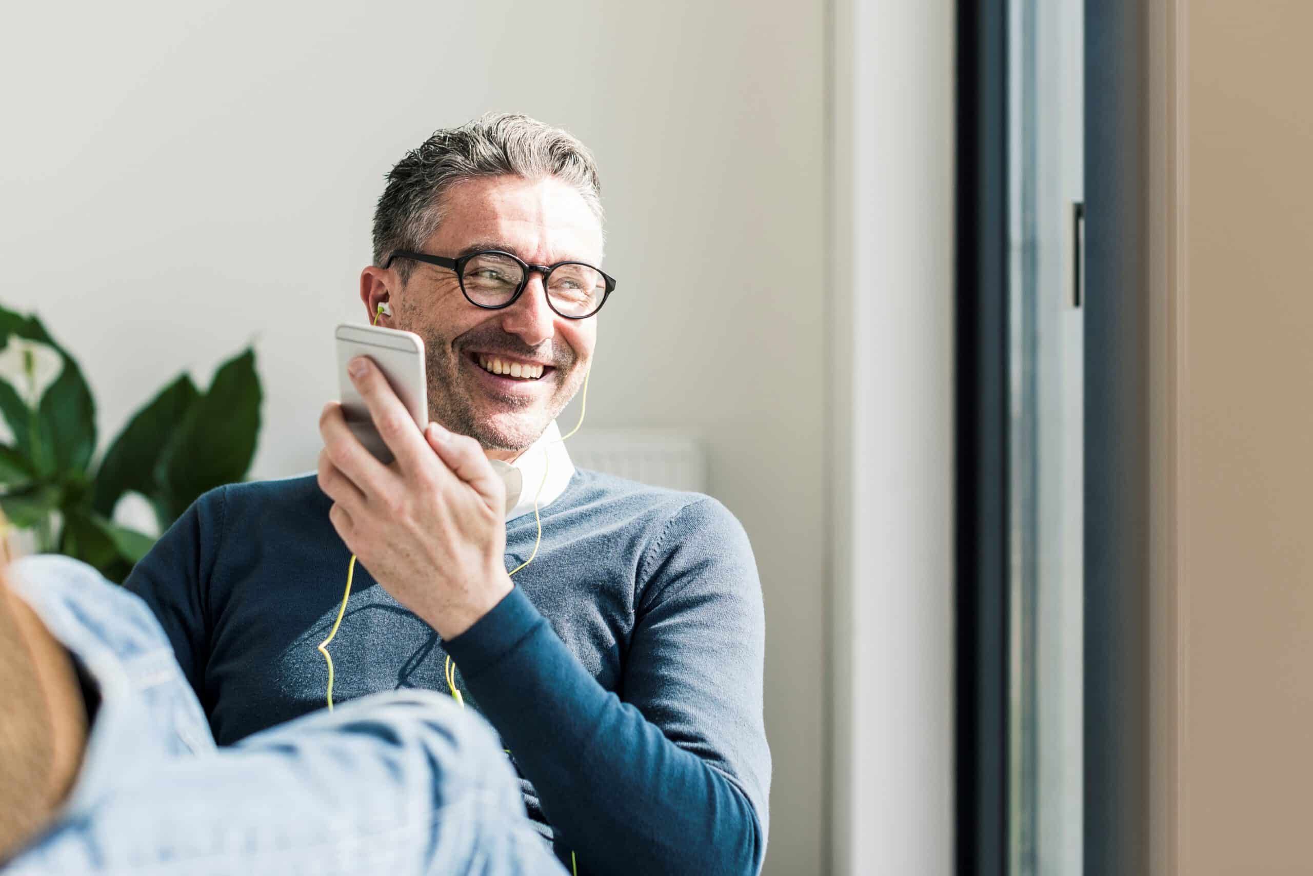 Portrait of smiling businessman using smartphone and earphones