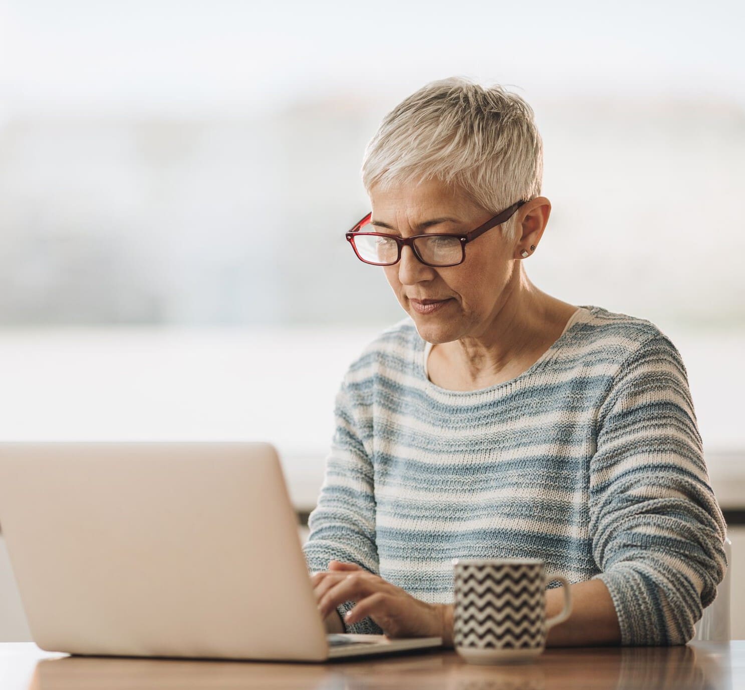 Senior woman using computer while surfing the net at home.